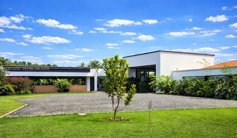 A modern, flat-roofed white house sits behind a gravel driveway and a green lawn — Finca La Pradera Montenegro Quindio Colombia, FL