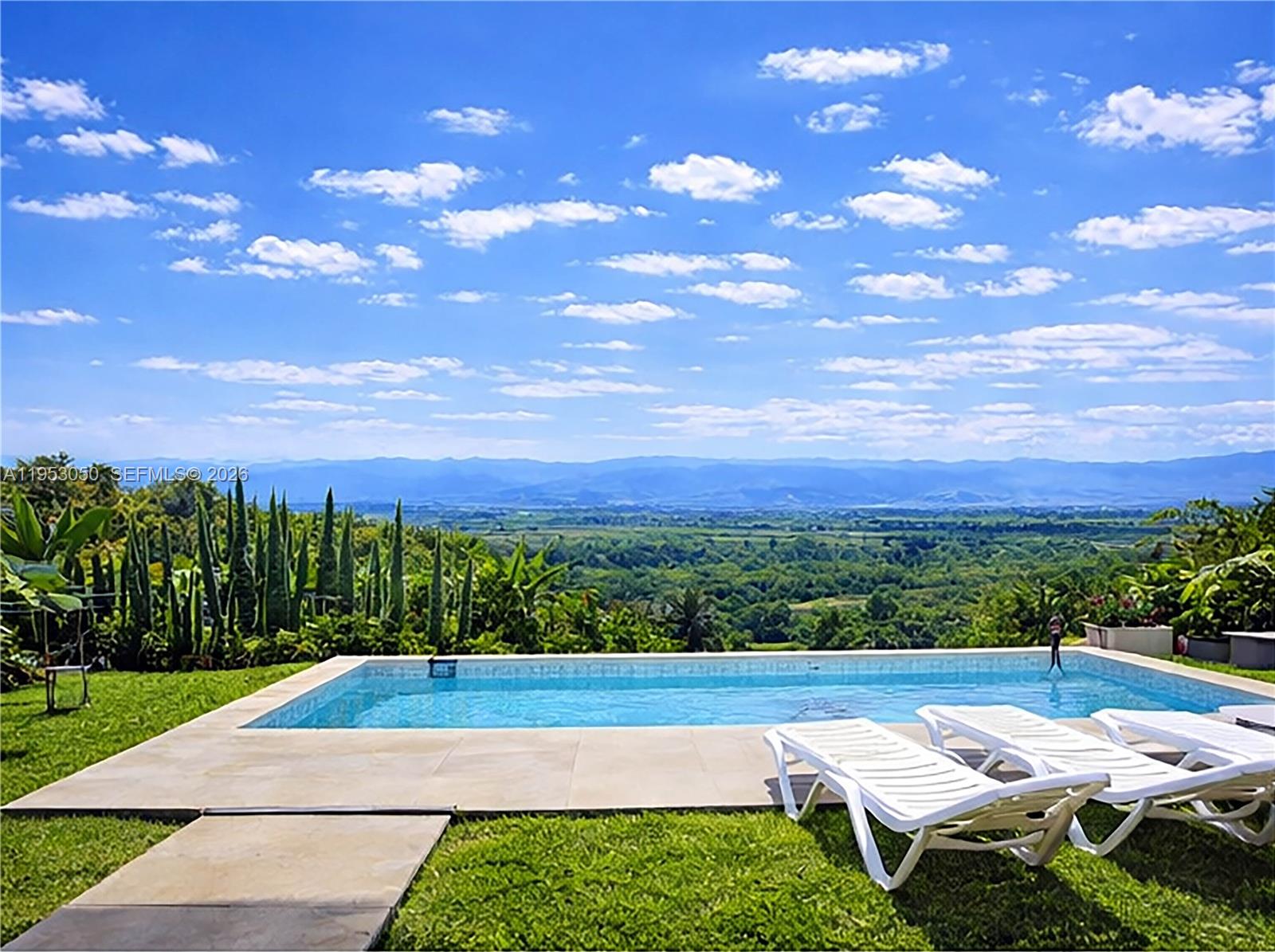 An outdoor swimming pool with lounge chairs overlooks a lush valley and distant mountains — Finca La Pradera Montenegro Quindio Colombia, FL