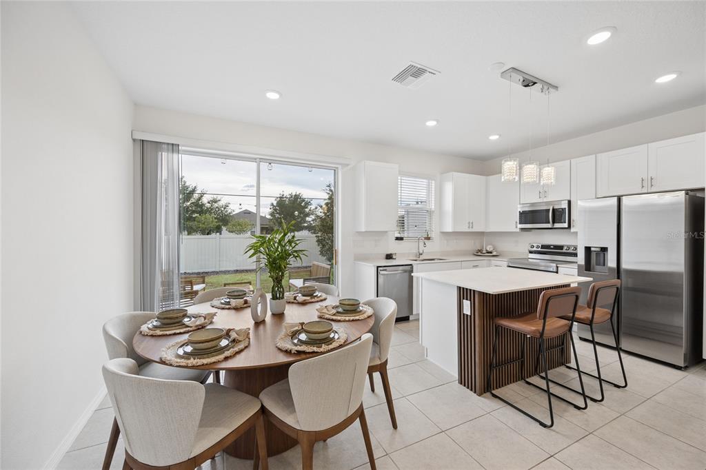 A dining area and kitchen feature white cabinetry, a wood-slatted island, and tile flooring — 1220 WYCLIFFE WAY, ST CLOUD, FL