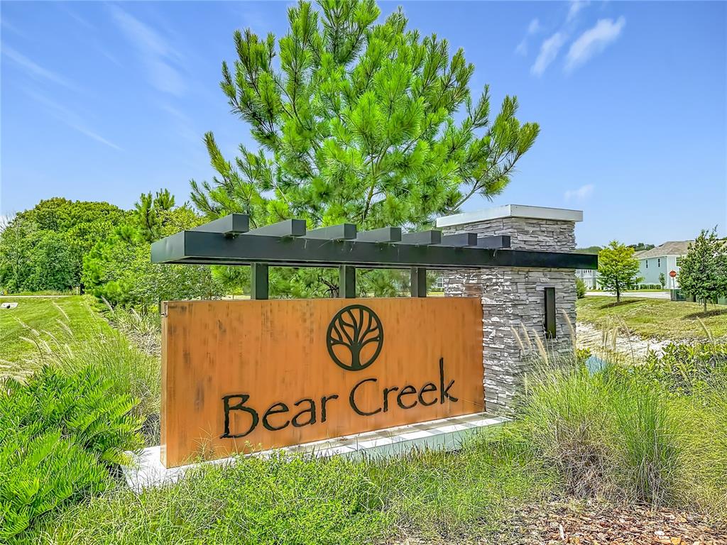 A metal and stone monument sign for Bear Creek stands in a grassy landscape — 12000 GRIZZLY LANE, NEW PORT RICHEY, FL