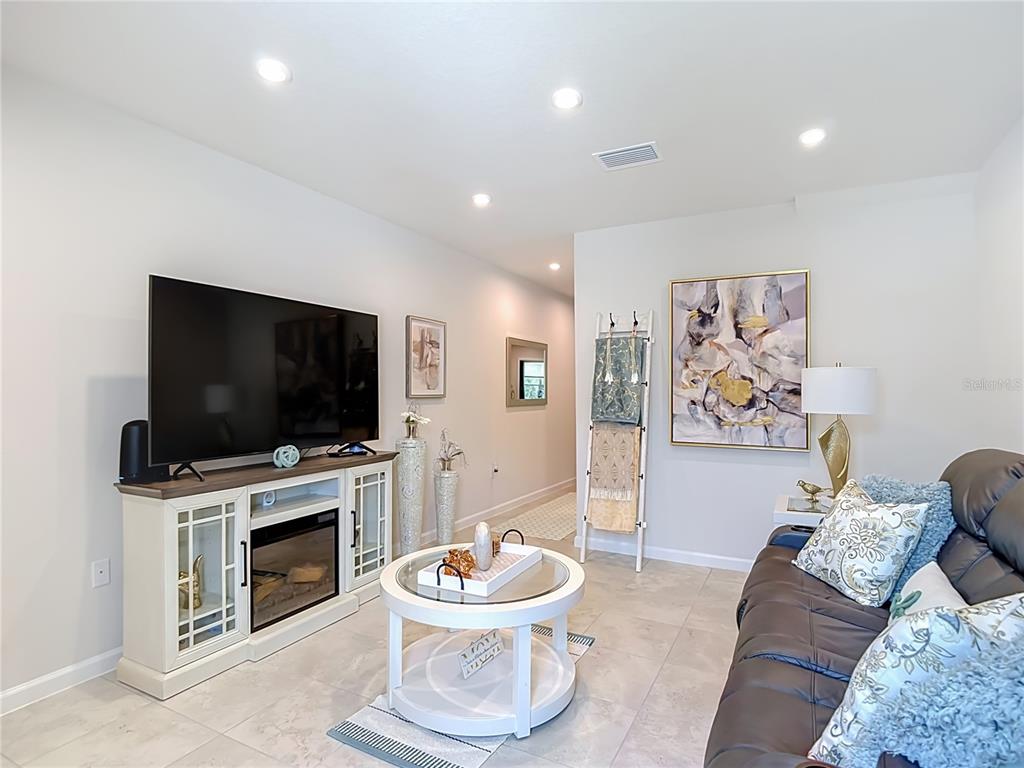 A living room features a television on a white media console, a coffee table, and sofa — 12000 GRIZZLY LANE, NEW PORT RICHEY, FL