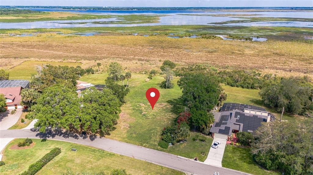 An aerial view shows a vacant grassy lot situated between two houses near a large lake — 0 HIDDEN HARBOR LANE, KISSIMMEE, FL