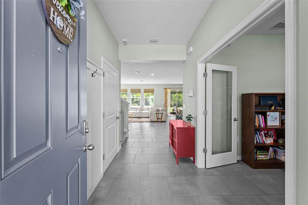 A tiled entryway leads into an open-concept living area with a red console table — 8693 BOWER BASS CIRCLE, WESLEY CHAPEL, FL