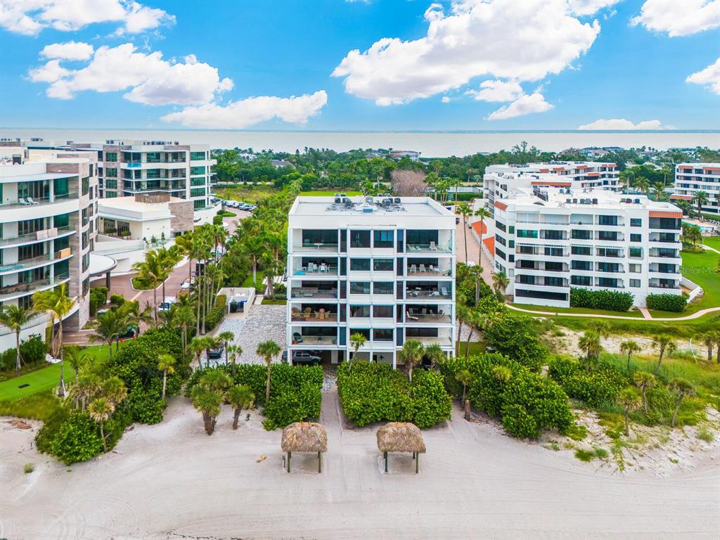 An aerial view shows a multi-story residential building situated on a sandy beach — 1511 GULF OF MEXICO DRIVE UNIT 201, LONGBOAT KEY, FL