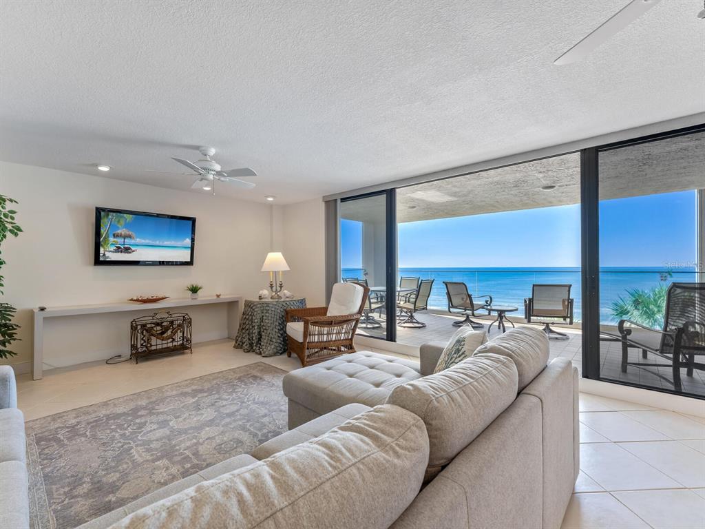 A living room with a sectional sofa, television, and a balcony overlooking the ocean — 1511 GULF OF MEXICO DRIVE UNIT 201, LONGBOAT KEY, FL