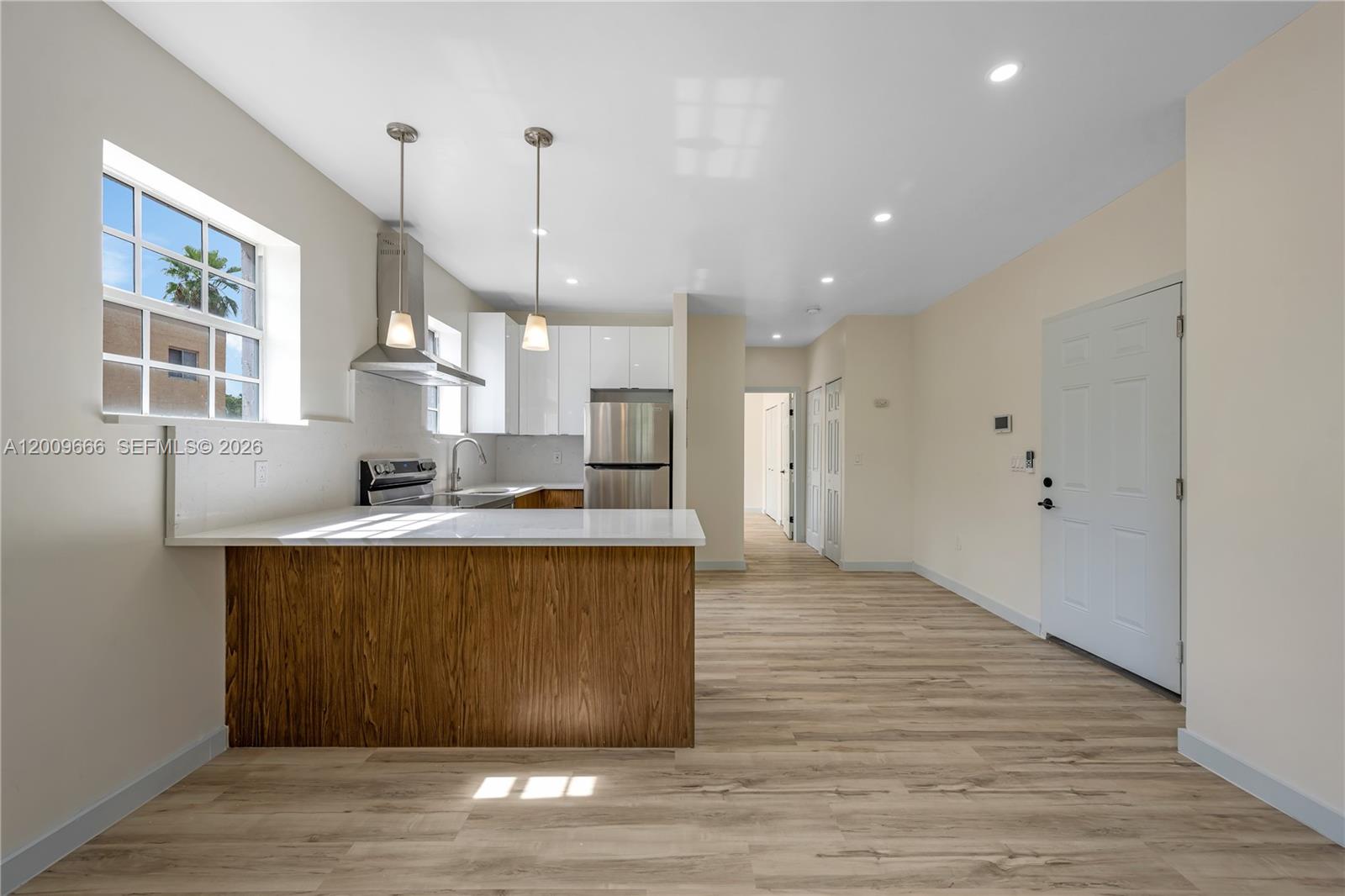A kitchen features a wood-paneled island, white cabinets, stainless steel appliances, and light wood flooring — 1132 NW 3rd St, Miami FL 33128, MIAMI, FL