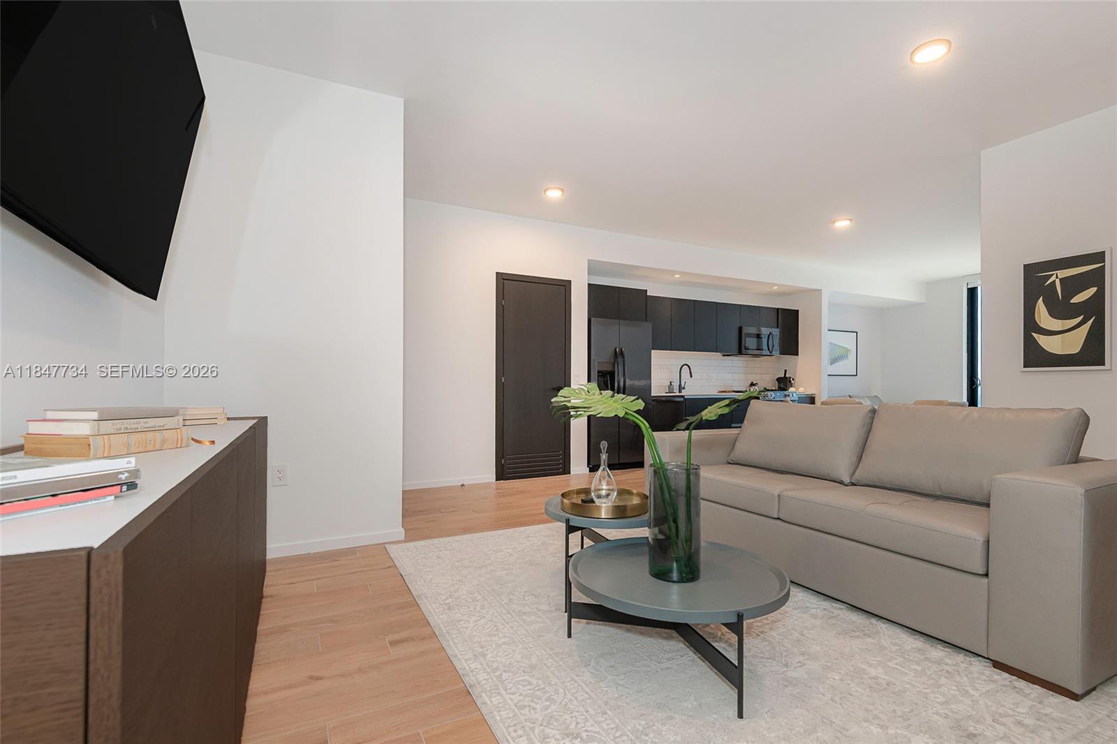 A modern living room features a grey sofa, two round coffee tables, and a kitchen — 398 NE 5th St # 4417, Miami FL 33132, MIAMI, FL