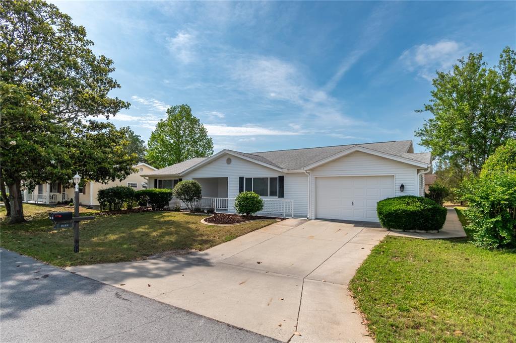 A single-story white house with a garage and a front porch sits on a lawn — 8156 SW 108TH LANE ROAD, OCALA, FL
