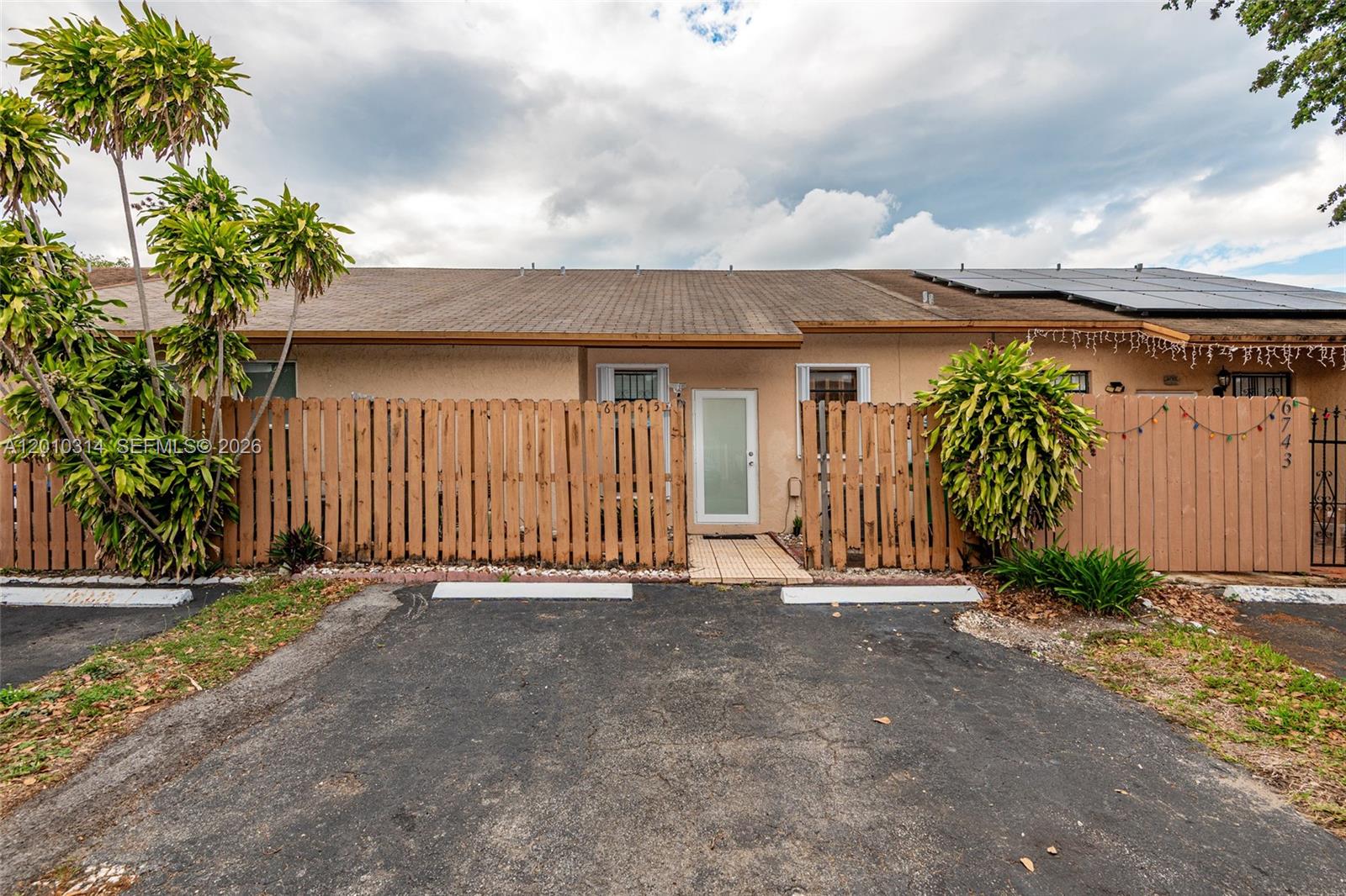 The exterior view shows a single-story house with a wooden fence and a paved driveway — 6745 NW 192nd Ln, Hialeah FL 33015, HIALEAH, FL