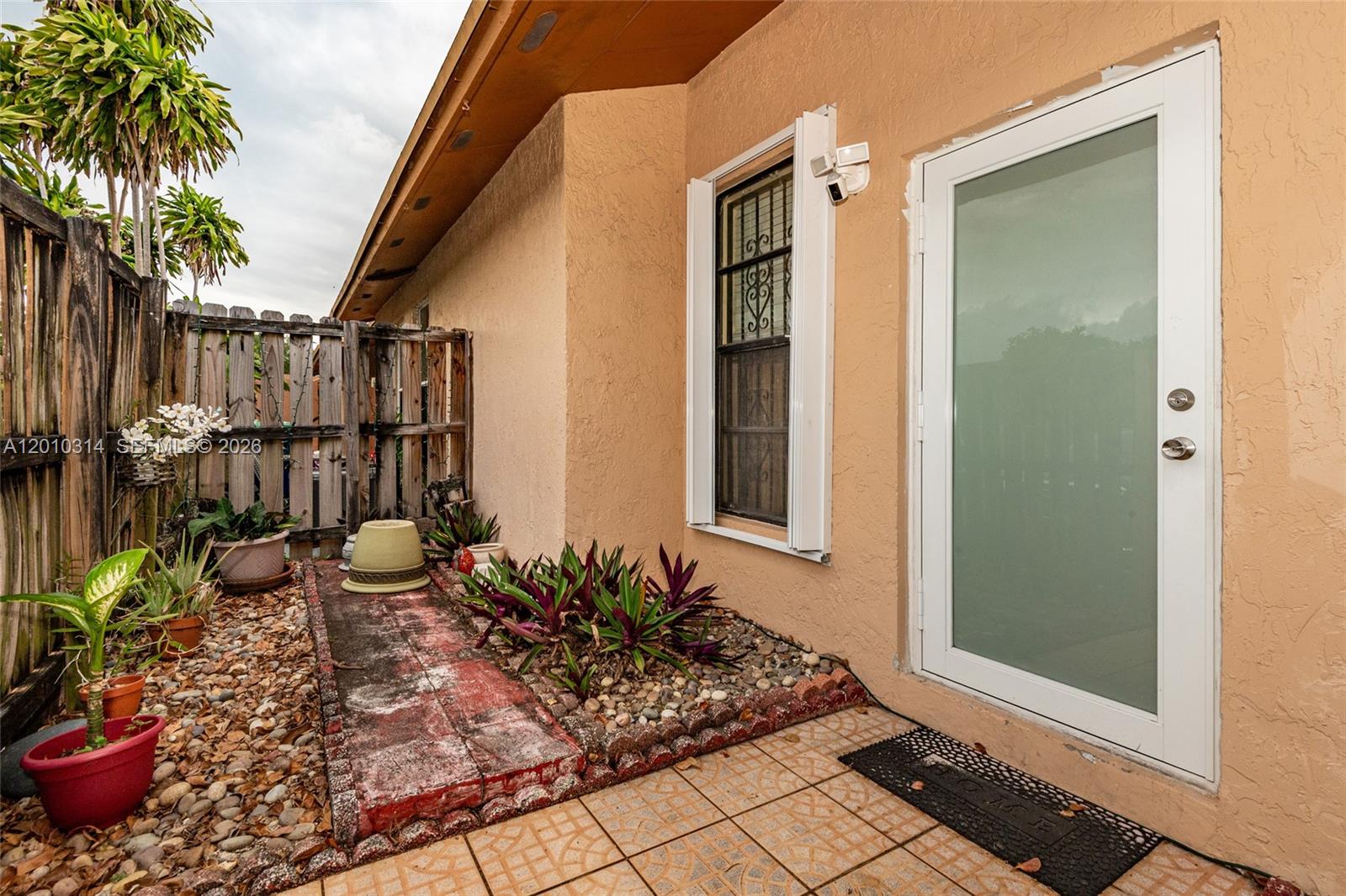 A side exterior view shows a tiled patio, a glass door, and a small garden — 6745 NW 192nd Ln, Hialeah FL 33015, HIALEAH, FL