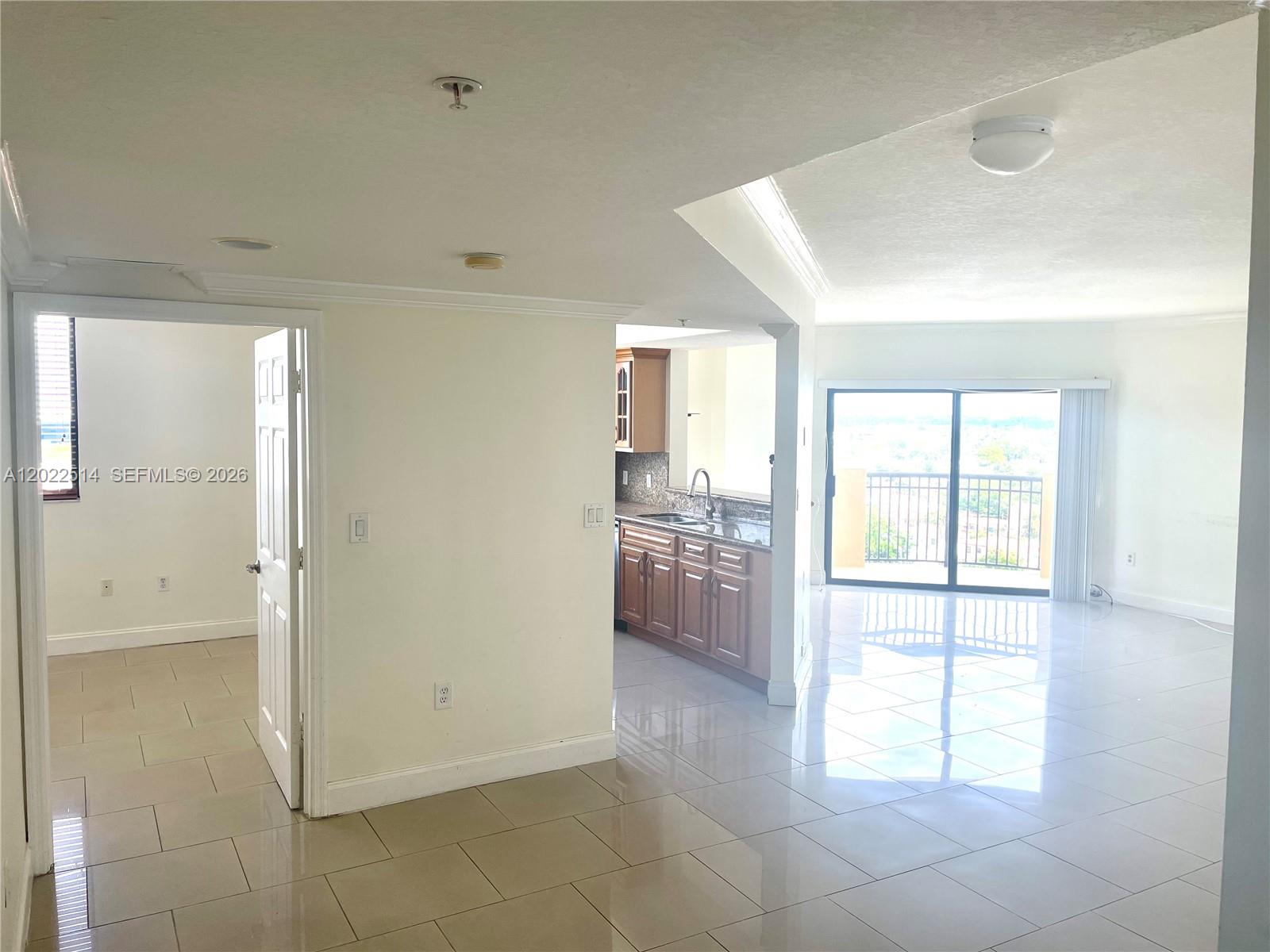 An interior view shows a tiled living area, an open kitchen with wood cabinets, and a balcony — 4242 NW 2nd St # 1002, Miami FL 33126, MIAMI, FL