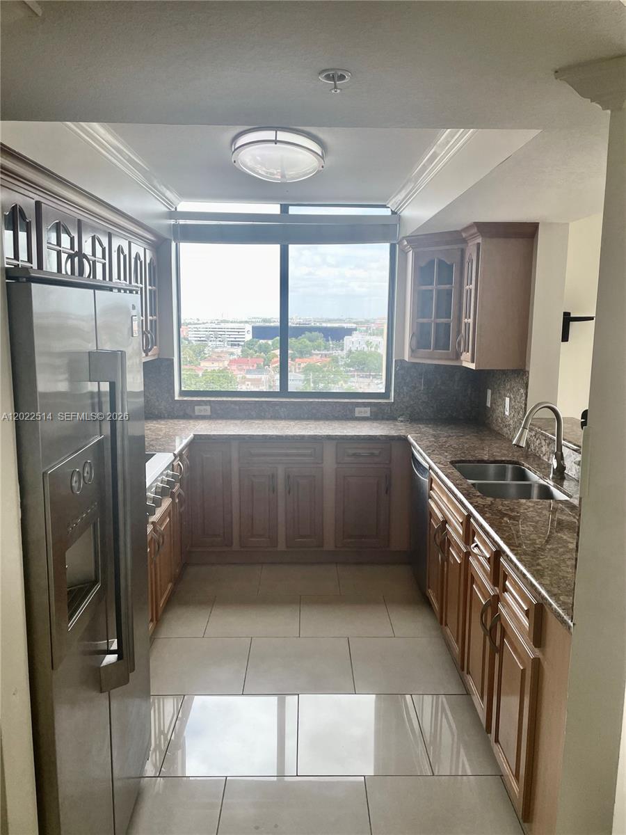 A galley kitchen features wood cabinets, granite countertops, stainless steel appliances, and a large window — 4242 NW 2nd St # 1002, Miami FL 33126, MIAMI, FL