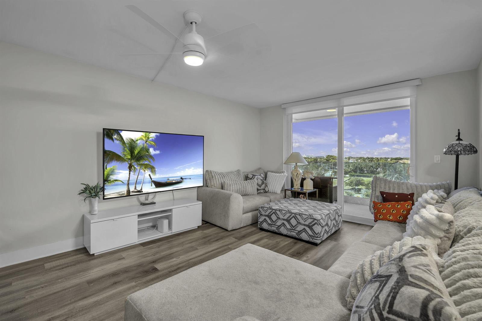 A living room features a white media console, a sectional sofa, and a sliding glass door — 2639 N Riverside Drive # 505, Pompano Beach FL 33062, POMPANO BEACH, FL