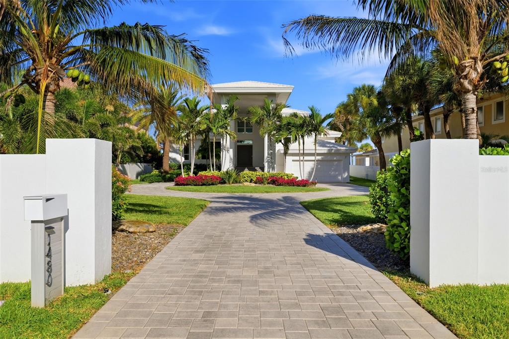A paved driveway leads to a modern two-story house surrounded by palm trees — 1480 GULF BOULEVARD, BELLEAIR BEACH, FL