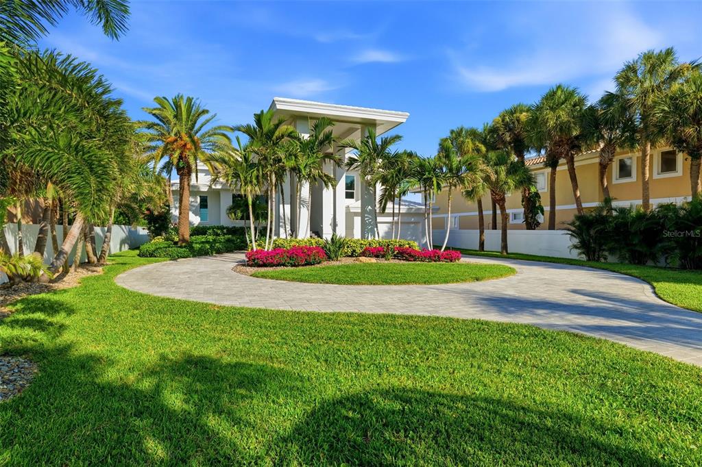 A circular paver driveway leads to the entrance of a modern house with palm trees — 1480 GULF BOULEVARD, BELLEAIR BEACH, FL