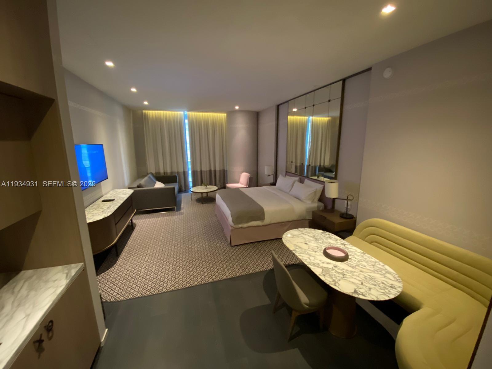 A hotel room features a bed, a seating area, and a dining table with bench seating — 801 S Miami Ave # 509, Miami FL 33130, MIAMI, FL