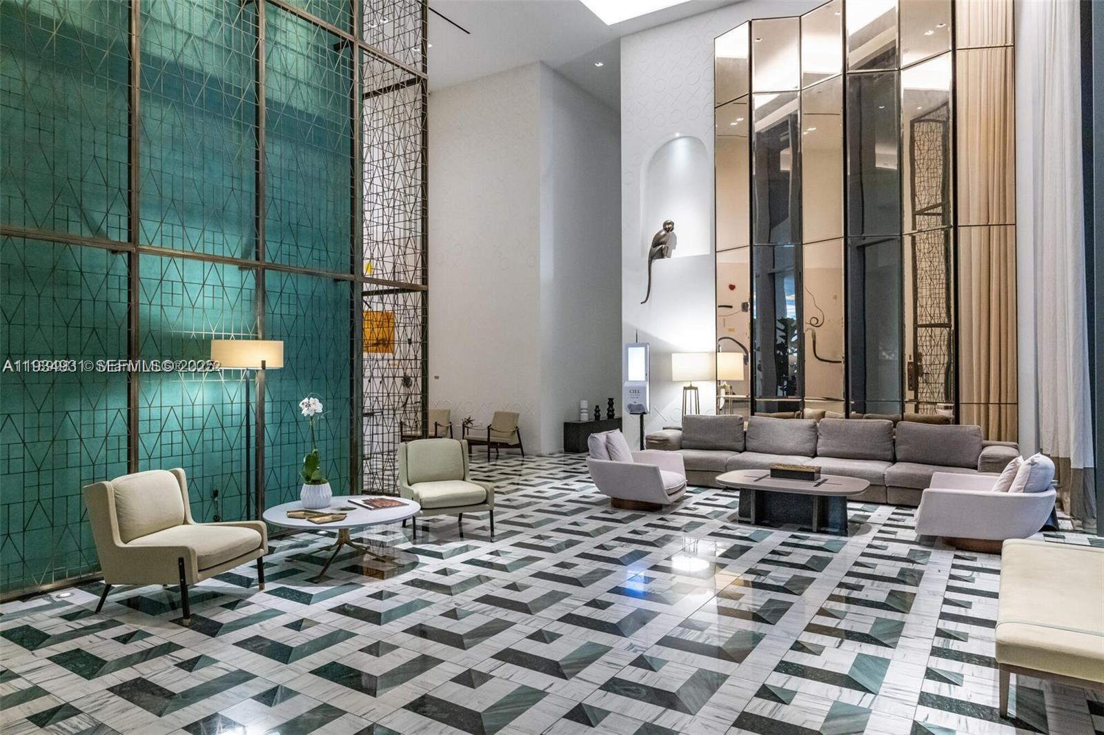 A modern lobby features a geometric marble floor, teal accent wall, and contemporary seating areas — 801 S Miami Ave # 509, Miami FL 33130, MIAMI, FL