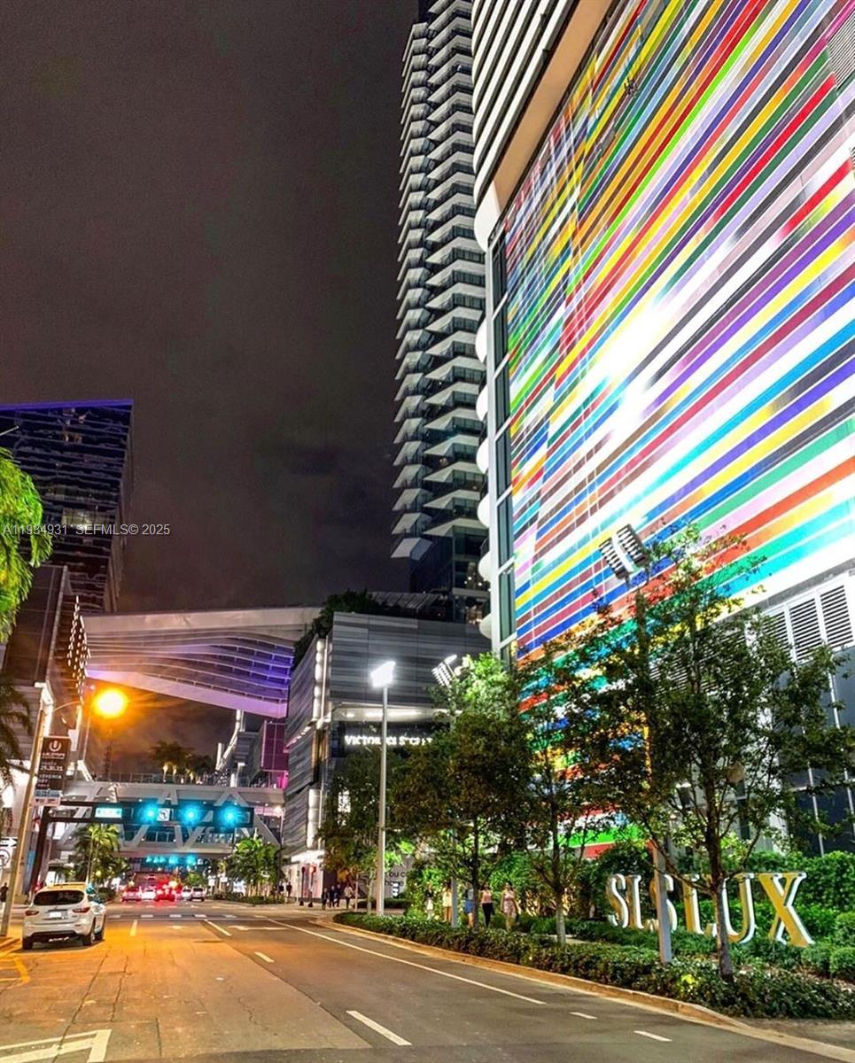 A street-level view of the SLS LUX building exterior at night with colorful facade lighting — 801 S Miami Ave # 509, Miami FL 33130, MIAMI, FL