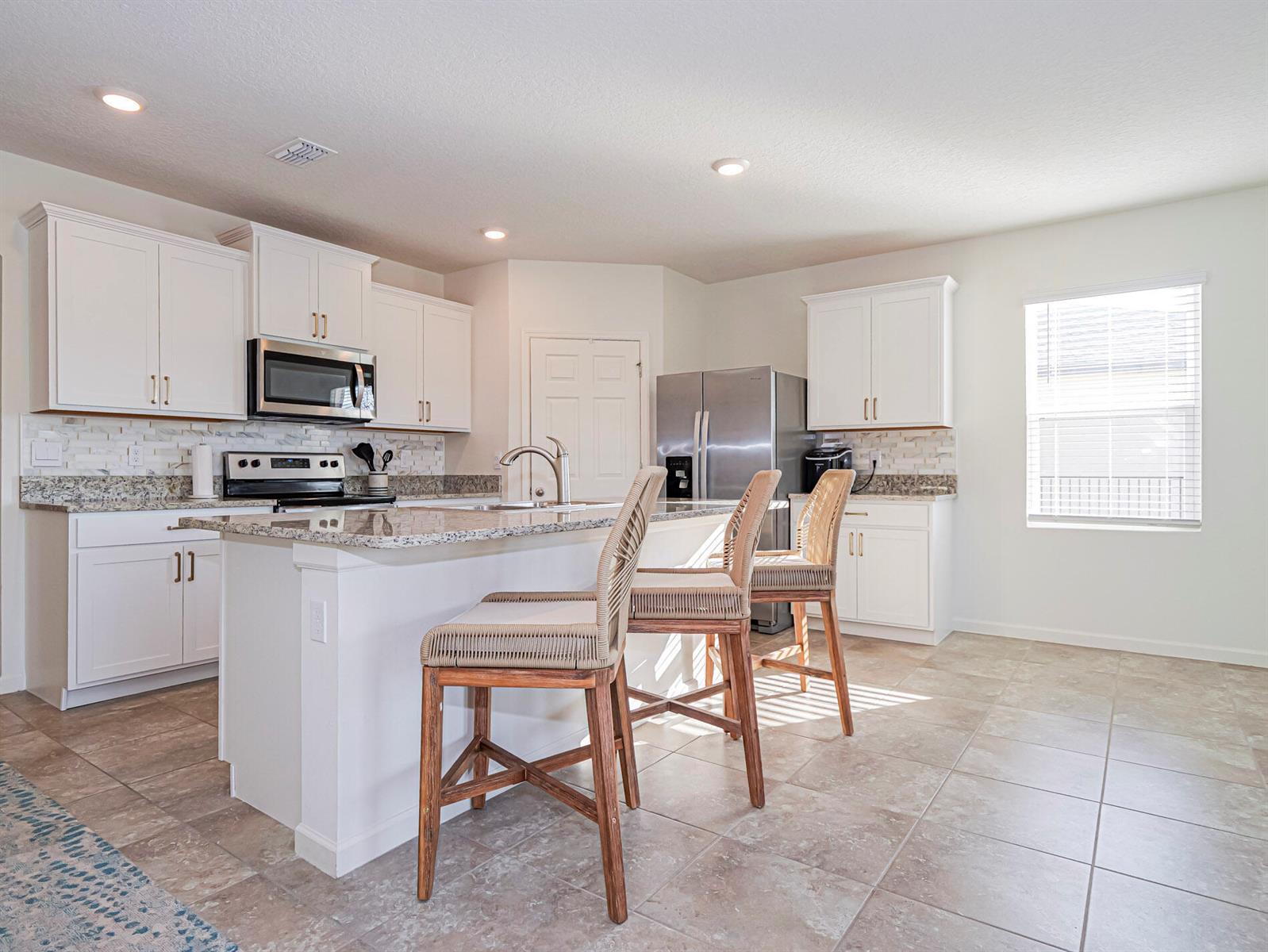 A kitchen features white cabinets, granite countertops, stainless steel appliances, and a central island — 4103 Keeson Circle, Vero Beach FL 32967, VERO BEACH, FL