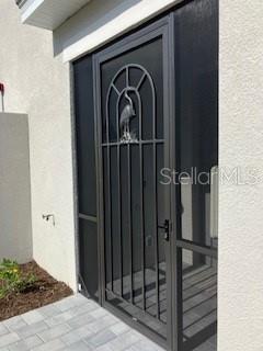 A dark metal screen door with a decorative heron design is installed on a home exterior — 17665 BORACAY COURT UNIT 101, VENICE, FL