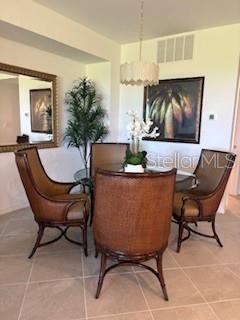 A dining room features a round glass table, four wicker chairs, and a hanging light fixture — 17665 BORACAY COURT UNIT 101, VENICE, FL