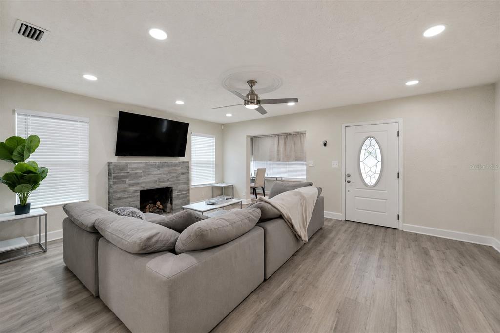 A living room features light wood-look flooring, a stone fireplace, and a ceiling fan — 2219 16TH STREET N, ST PETERSBURG, FL