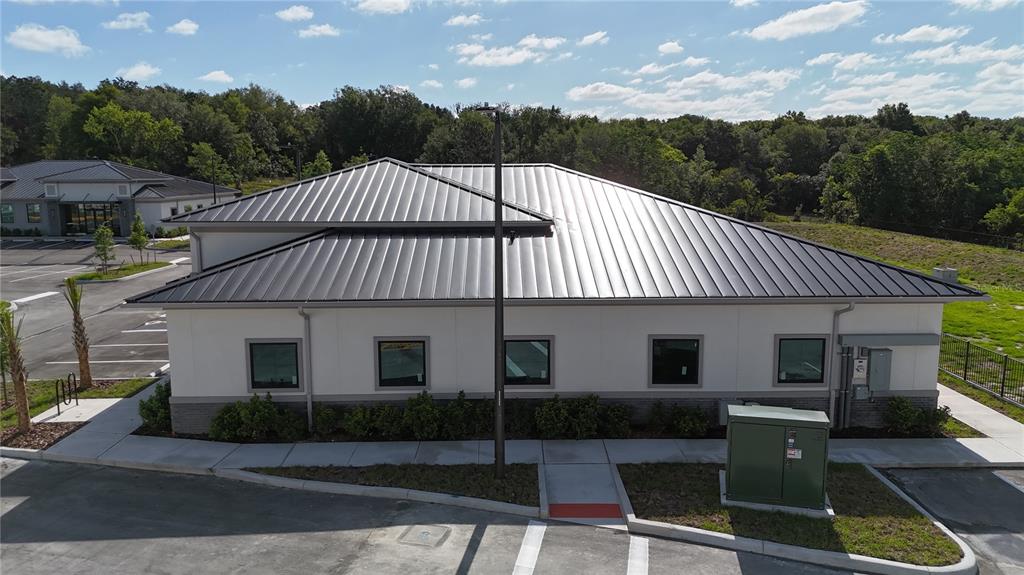 An exterior view of a modern commercial building with a metal roof and parking lot — 2835 OCOEE APOPKA ROAD UNIT 13, APOPKA, FL