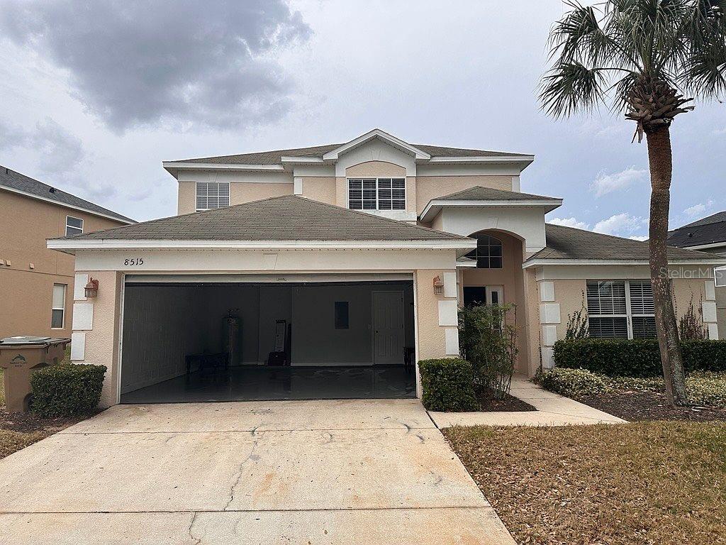 A two-story suburban house features a tan stucco exterior, a two-car garage, and a palm tree — 8515 PALM HARBOR DRIVE, KISSIMMEE, FL