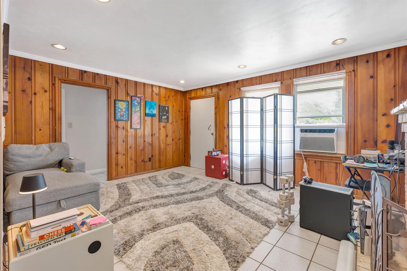 A living room features wood-paneled walls, tile flooring, a gray sectional sofa, and a rug — 505 Foresteria Drive, Lake Park FL 33403, LAKE PARK, FL