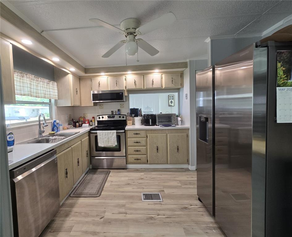 A kitchen features light wood cabinets, stainless steel appliances, and wood-look flooring — 2011 OAK GROVE DRIVE UNIT 39, ZELLWOOD, FL
