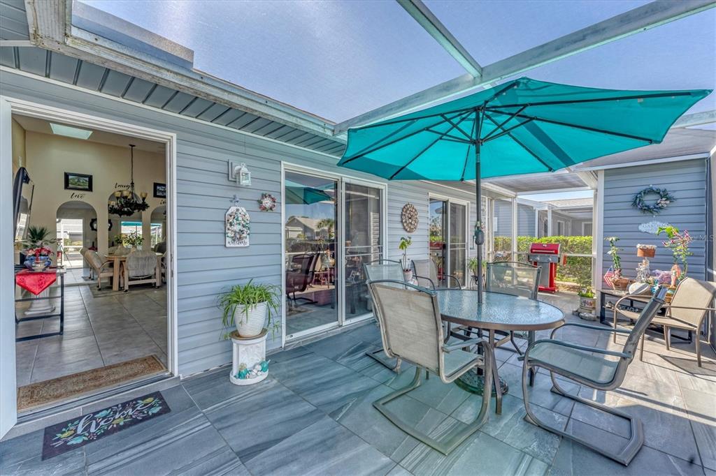 A covered patio with gray tile flooring, a dining set, and a teal umbrella — 3300 LOVELAND BOULEVARD UNIT 1201, PUNTA GORDA, FL