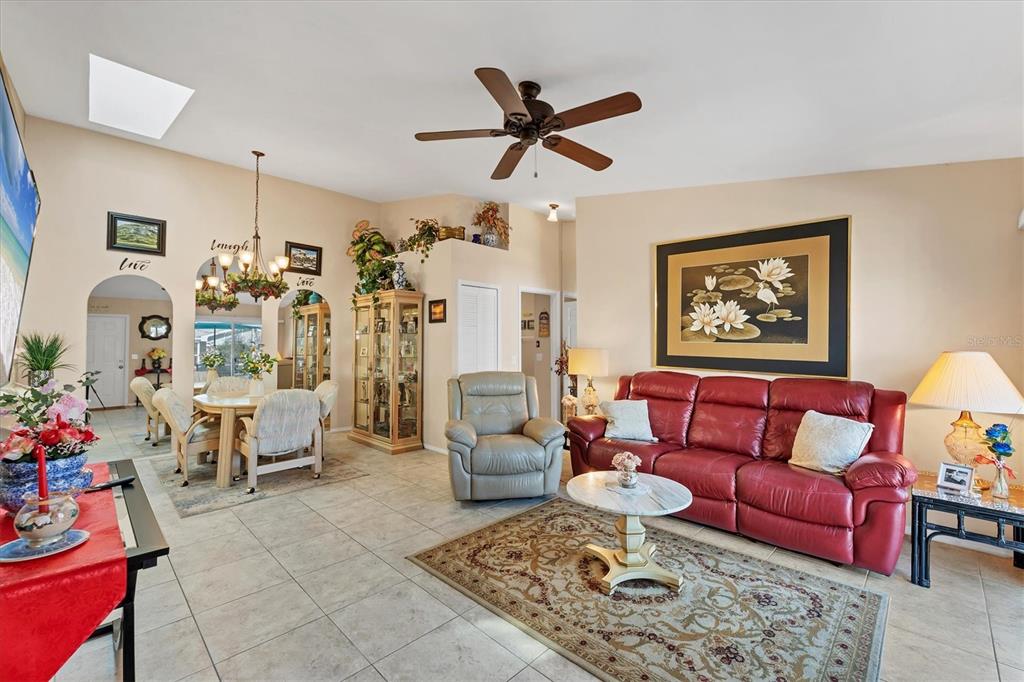 A living room with tile floors, a red leather sofa, and an adjacent dining area — 3300 LOVELAND BOULEVARD UNIT 1201, PUNTA GORDA, FL