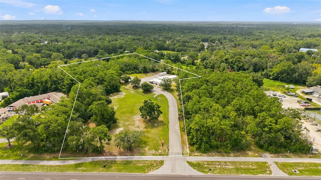 An aerial view shows a wooded lot with a paved driveway and a small building — 15464 CORTEZ BOULEVARD, BROOKSVILLE, FL