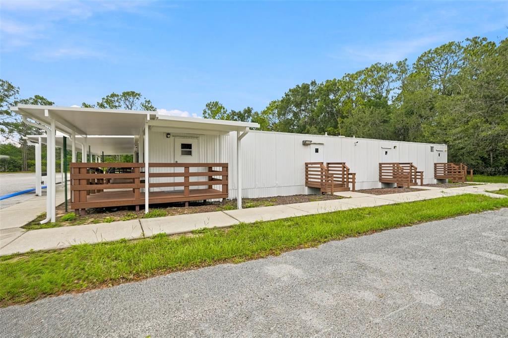 A long, white modular building features a covered porch and several wooden entrance decks — 15464 CORTEZ BOULEVARD, BROOKSVILLE, FL