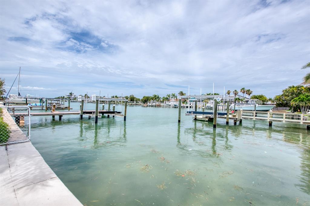 A view of a canal with boat docks and calm water under a cloudy sky — 12125 6TH STREET E, TREASURE ISLAND, FL