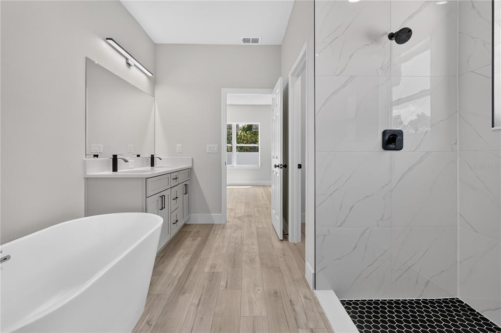 A modern bathroom features a freestanding tub, a double vanity, and a glass-enclosed tiled shower — 867 CORNELIA AVENUE SE, PALM BAY, FL
