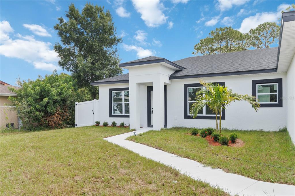A white single-story house with a dark roof, black-trimmed windows, and a concrete walkway — 867 CORNELIA AVENUE SE, PALM BAY, FL