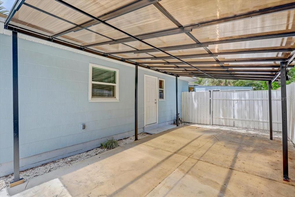 A concrete carport with a translucent roof cover is attached to a light blue house — 2901 DR MARTIN LUTHER KING JR STREET S, ST PETERSBURG, FL