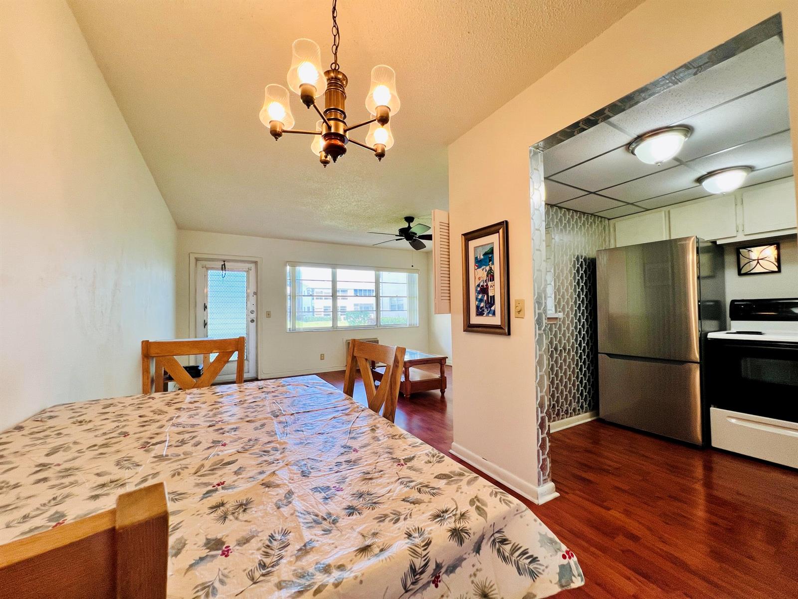 A dining area with a patterned tablecloth leads into a kitchen with stainless steel appliances — 8 Northampton A, West Palm Beach FL 33417, WEST PALM BEACH, FL