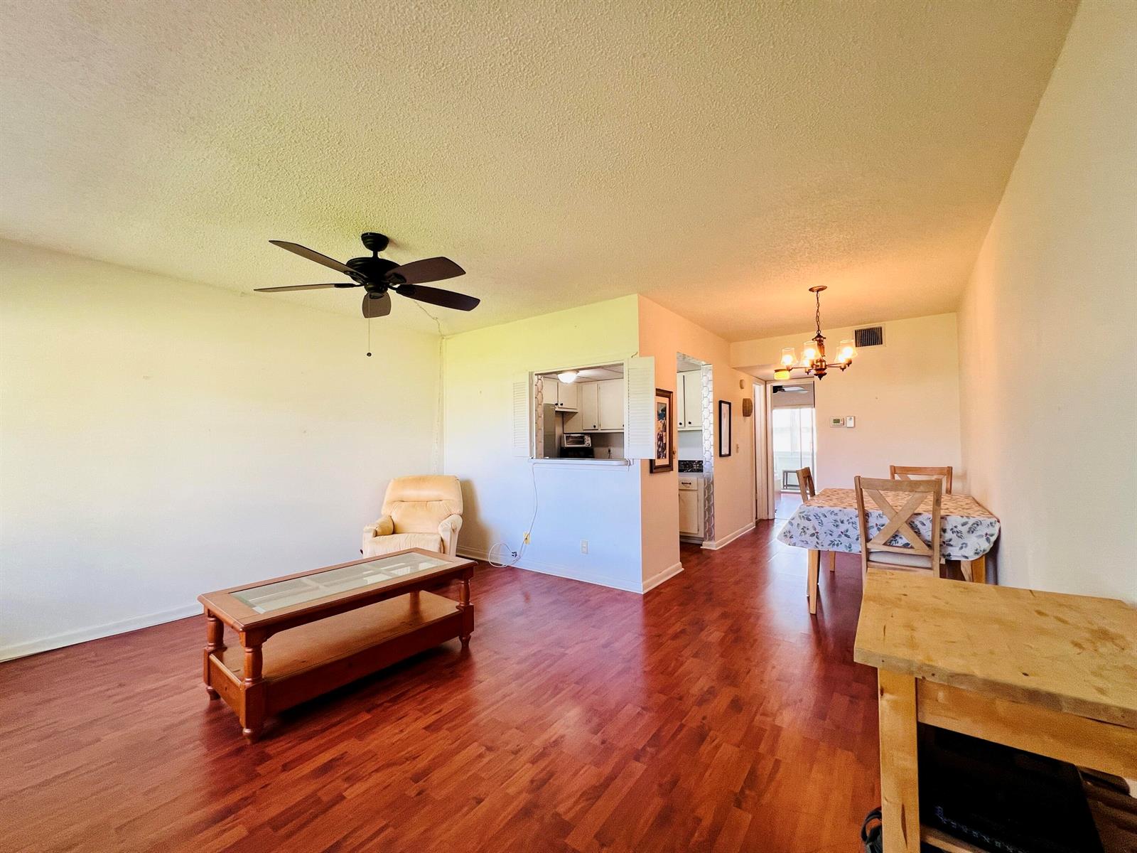 A living and dining area with wood-look flooring, a ceiling fan, and a kitchen pass-through — 8 Northampton A, West Palm Beach FL 33417, WEST PALM BEACH, FL