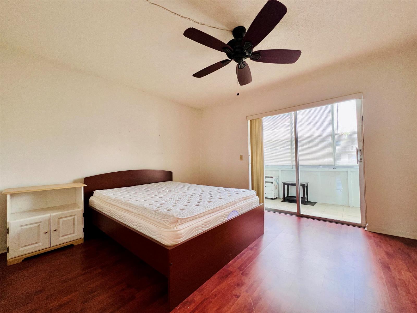 A bedroom features a bed, a small cabinet, a ceiling fan, and a sliding glass door — 8 Northampton A, West Palm Beach FL 33417, WEST PALM BEACH, FL