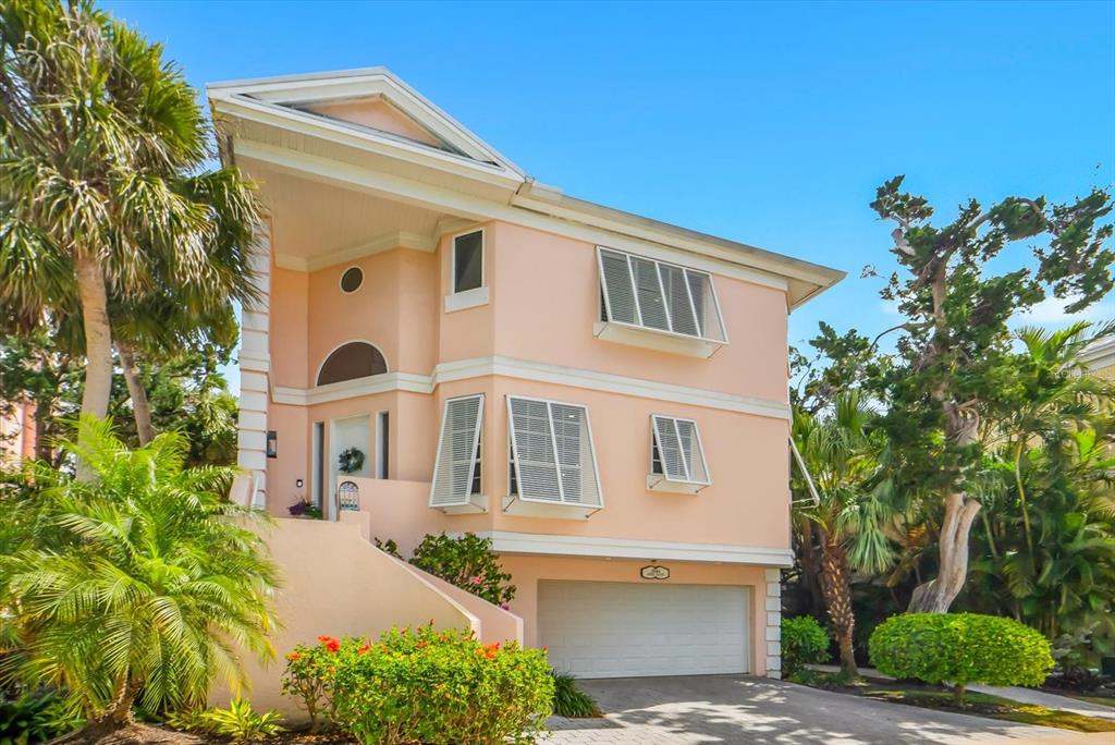 A two-story peach-colored house with a garage, white shutters, and surrounding tropical landscaping — 3941 HAMILTON CLUB CIRCLE UNIT 9, SARASOTA, FL