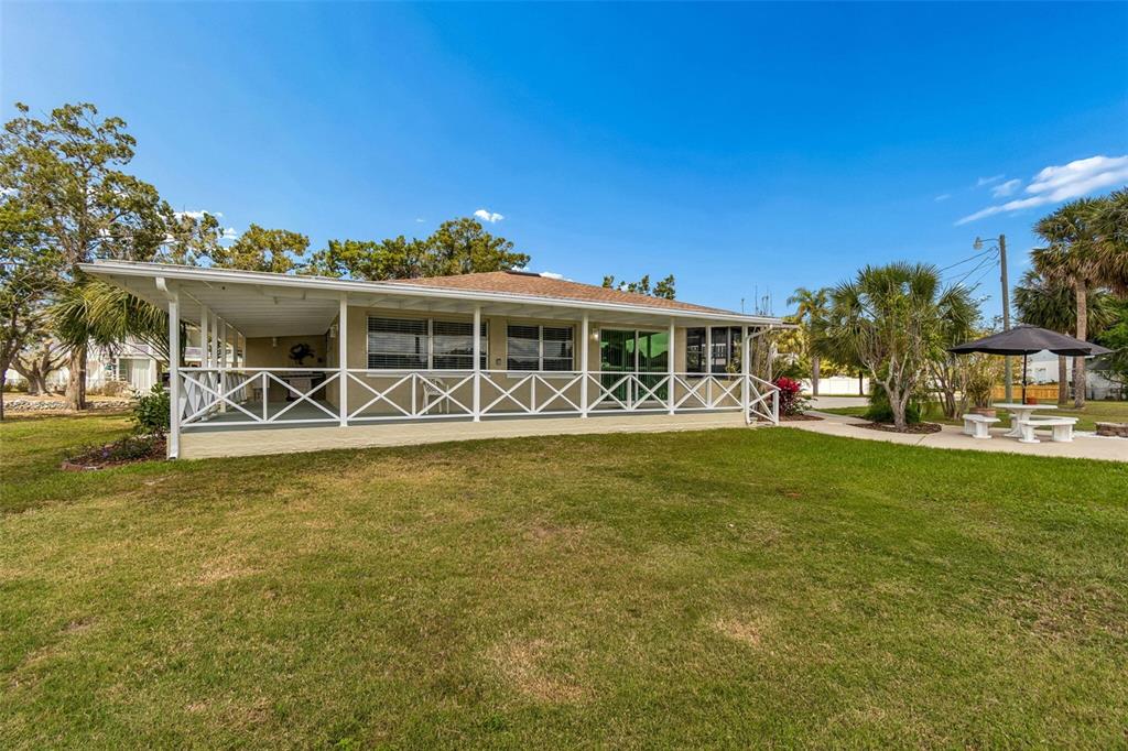 A single-story house features a large covered porch with white lattice railings and lawn — 14539 COFFEY LANE, HUDSON, FL