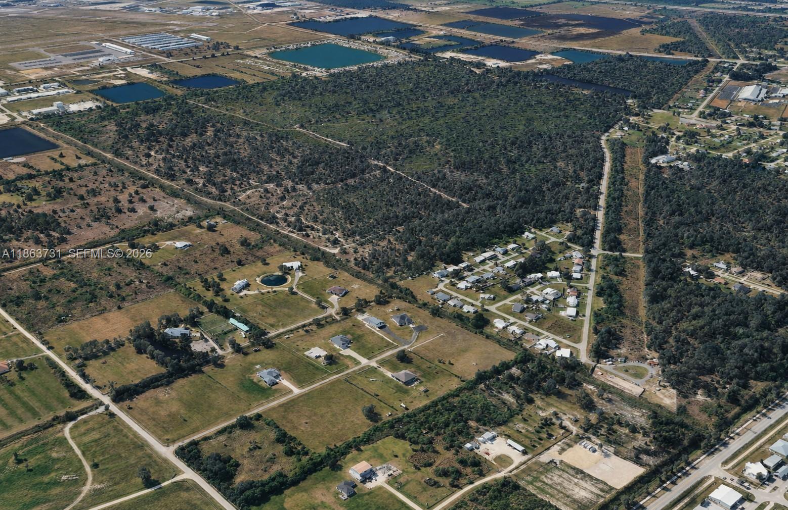 This aerial view shows a rural landscape with scattered houses, wooded areas, and several ponds — 710 Pompano Ter, Punta Gorda FL 34224, PUNTA GORDA, FL