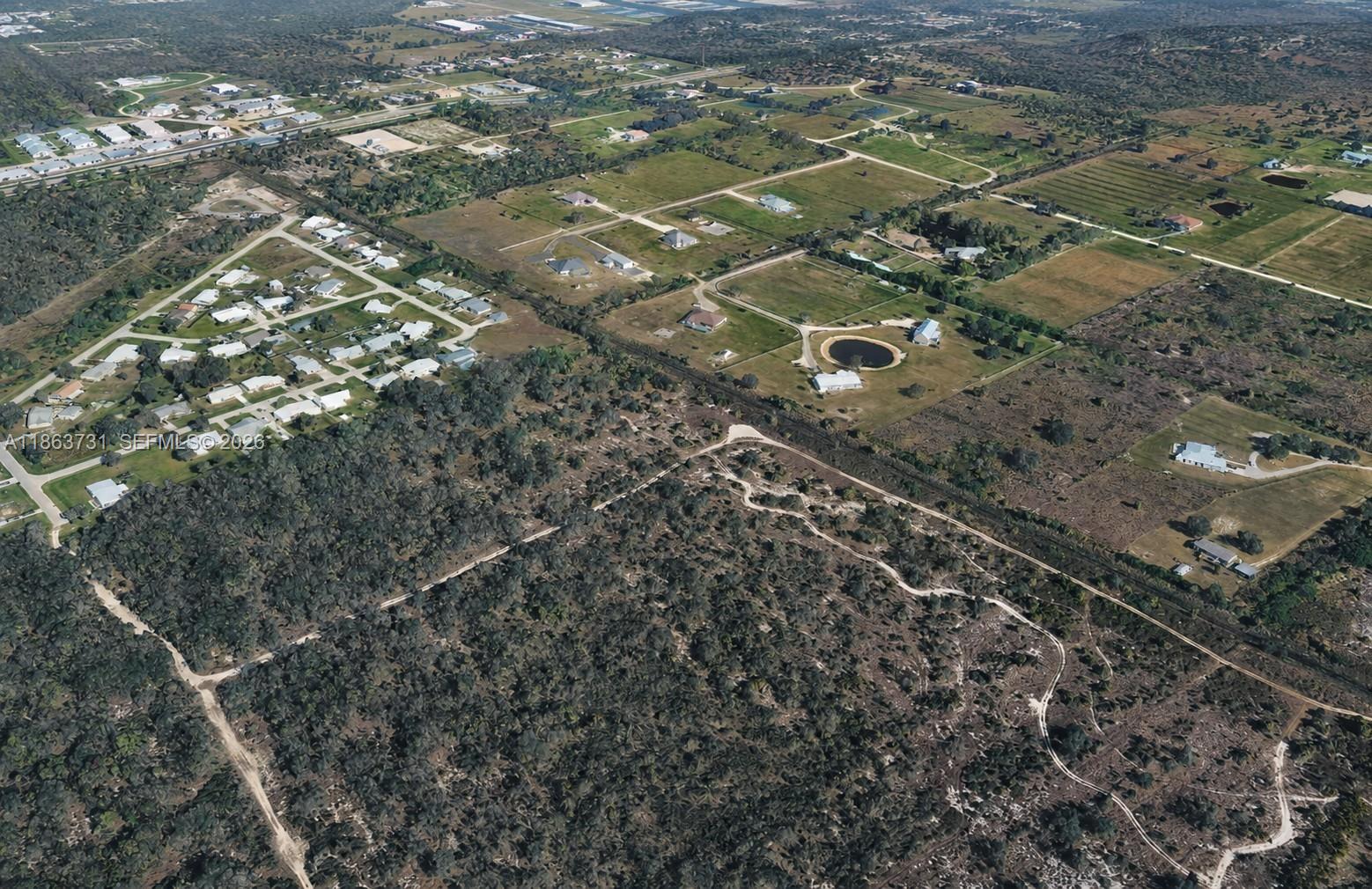An aerial view shows a residential neighborhood bordering a large, undeveloped wooded area — 710 Pompano Ter, Punta Gorda FL 34224, PUNTA GORDA, FL