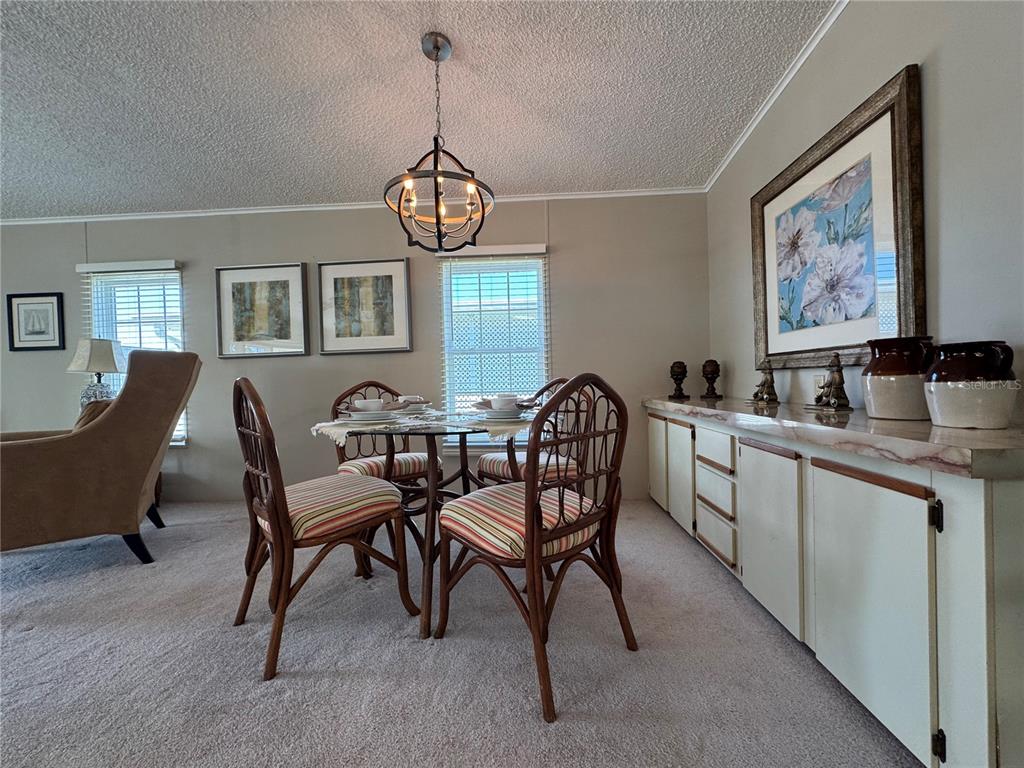 A dining area features a glass-top table, rattan chairs, a chandelier, and a built-in sideboard — 6394 LOLLY BAY LOOP NE, WINTER HAVEN, FL
