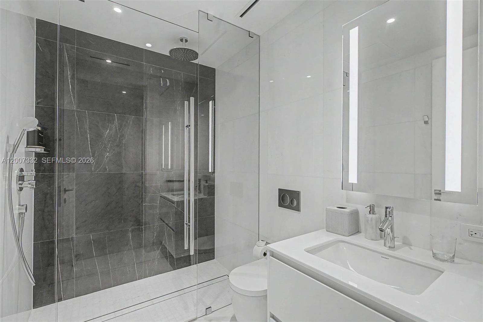 A modern bathroom features a glass-enclosed walk-in shower with dark marble tile and white vanity — 300 Biscayne Blvd Way # 3203, Miami FL 33131, MIAMI, FL