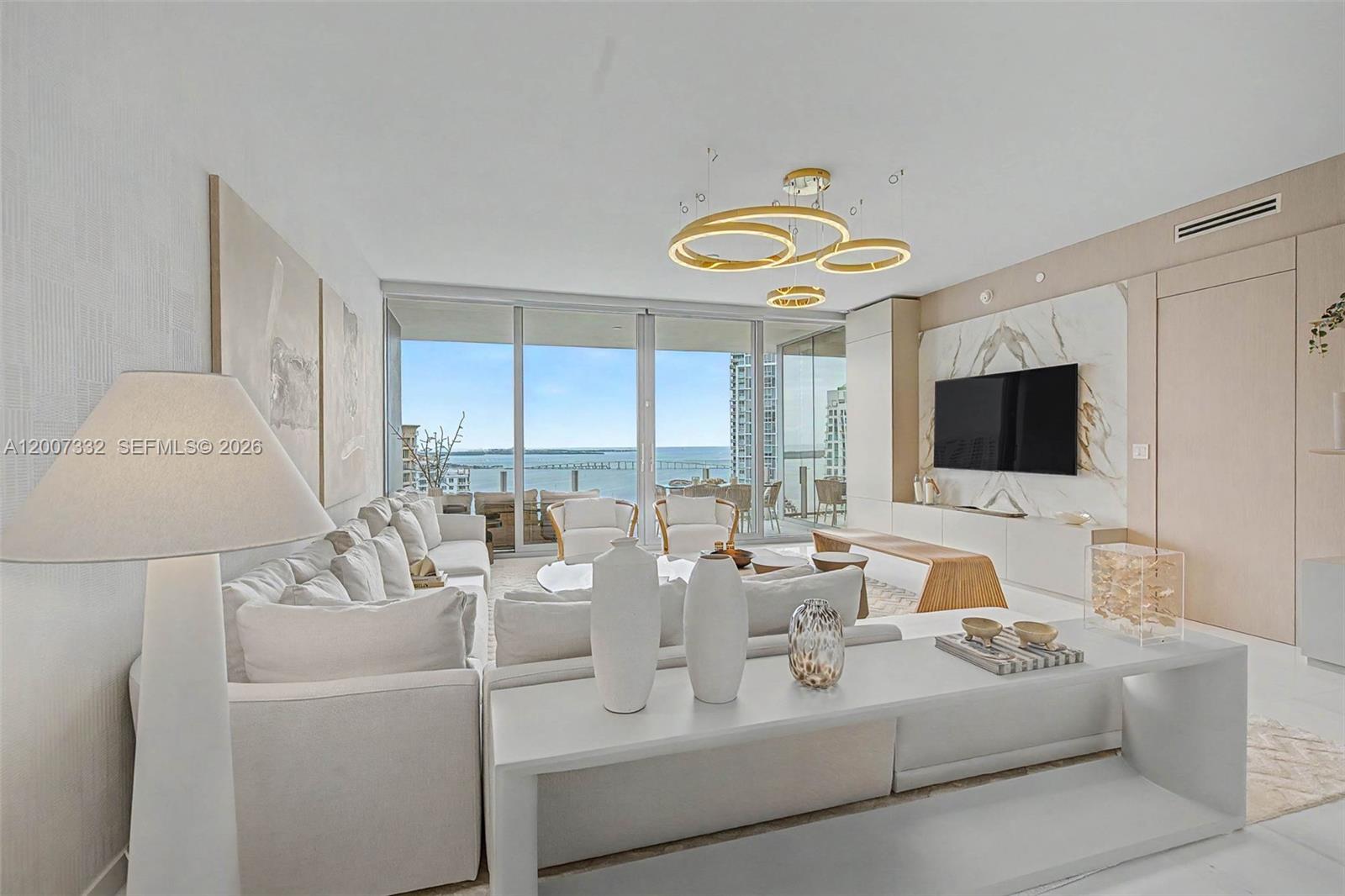 A modern living room features a white sectional sofa, marble accent wall, and ocean views — 300 Biscayne Blvd Way # 3203, Miami FL 33131, MIAMI, FL