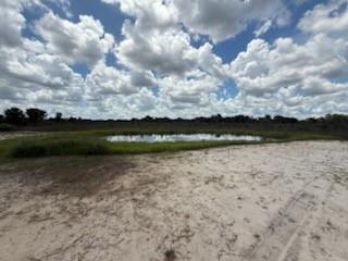 A small pond sits in the middle of a sandy, grassy field under a cloudy sky — 19374 NW 302, Okeechobee FL 34972, OKEECHOBEE, FL