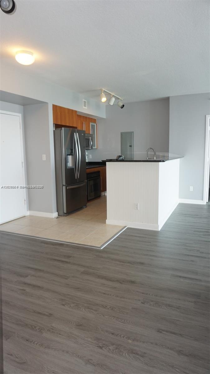 A kitchen with stainless steel appliances, wood cabinets, and a breakfast bar overlooks a living area — 325 S Biscayne Blvd # 2022, Miami FL 33131, MIAMI, FL
